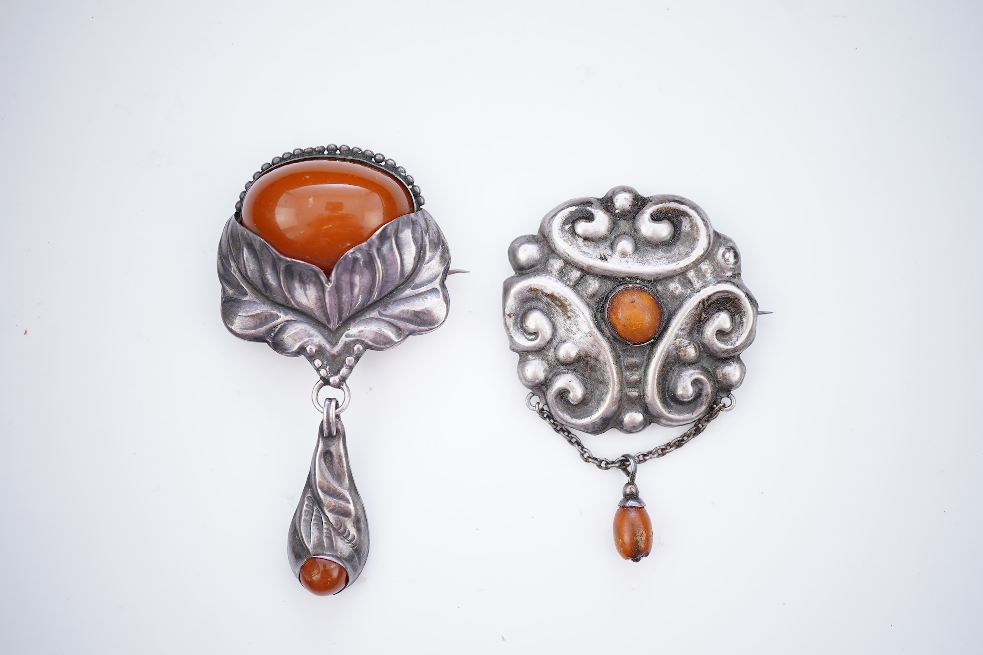 Two Arts & Crafts silver and amber pendant brooches, probably Denmark, early 20th century